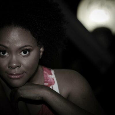Black Woman with Black hair in photo with black background shadow.